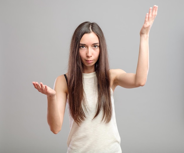 Attractive woman holding her hands out saying that she does not know isolated over gray background