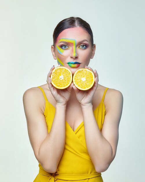 Attractive woman holds orange slices in front of her face