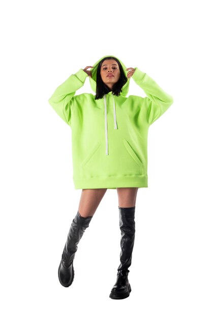 Attractive woman of Latin appearance wears a green hooded hoodie on a white background The girl looks sexy and happy The elegant brunette is wearing a dark sweatshirt Allseason clothing