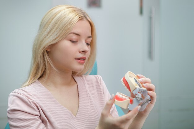 Привлекательная женщина смотрит на стоматологическую форму в ожидании осмотра зубов стоматологом