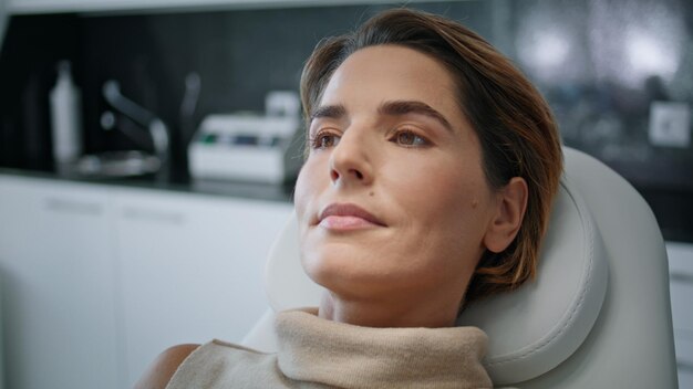 Attractive woman lying cosmetology chair ready to beauty procedures close up