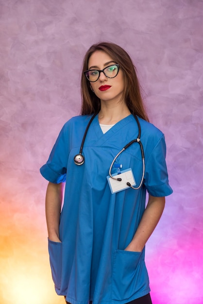 Foto donna attraente in uniforme medica in posa su sfondo astratto. dottoressa o infermiera