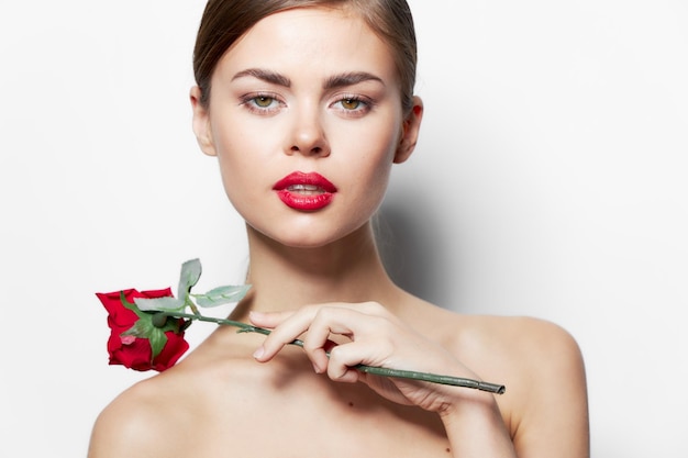 Attractive woman naked shoulders Red lips clear skin rose flower cropped view light background