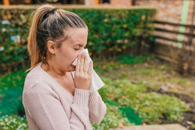 Attractive woman outdoor with tissue having allergy.