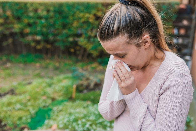 Attractive woman outdoor with tissue having allergy