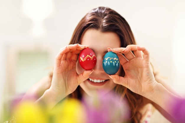 Foto donna attraente che dipinge le uova di pasqua a casa