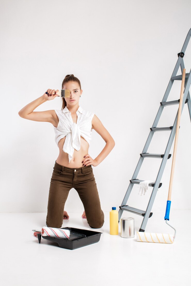 Attractive woman painting wall in her house. beautiful woman holding a paint brush