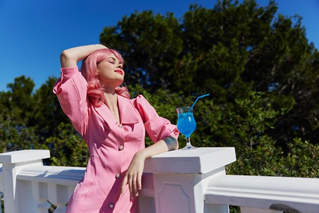 Attractive woman in pink dress outdoors with cocktail happy female relaxing high quality photo