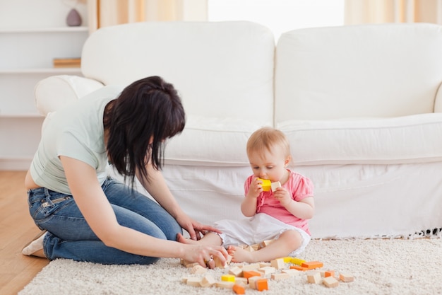 Attractive woman playing with her baby in while sitting on a carpet