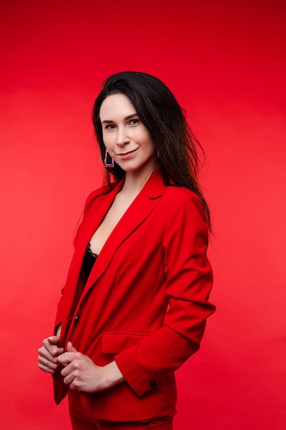 Attractive woman poses for the office magazine and smiles, picture isolated on red wall