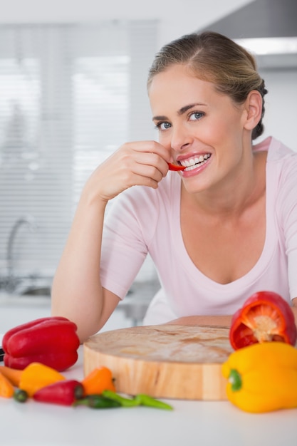 Donna attraente che posa mentre mangia le verdure