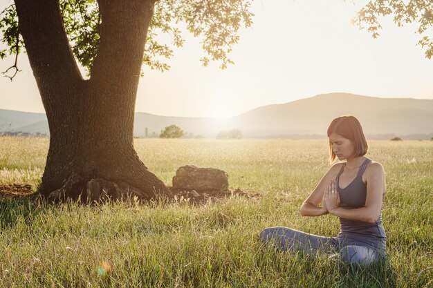 Attractive woman practices yoga in nature in summer