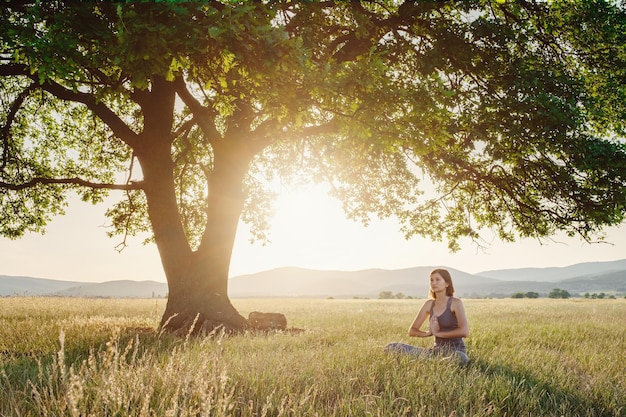 Attractive woman practices yoga in nature in summer