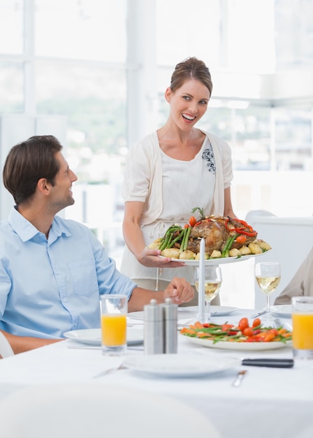 Attractive woman presenting a roast chicken