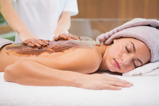 Attractive woman receiving chocolate back mask at spa center