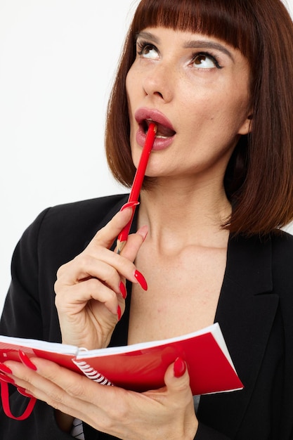 Attractive woman red notepad and pencil posing light background