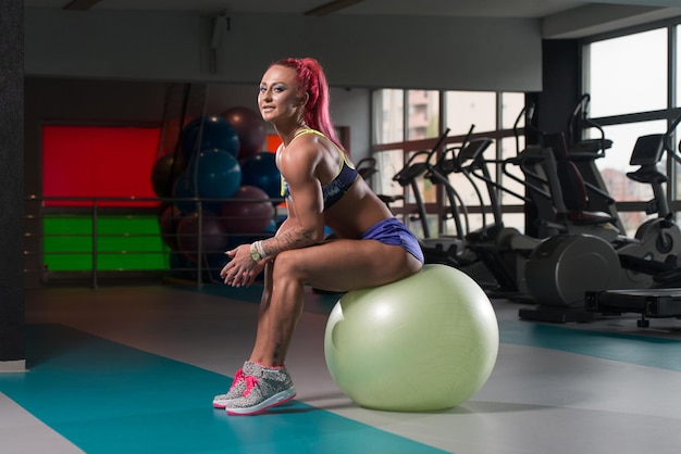 Attractive Woman Resting On Ball After Exercise In Fitness Center