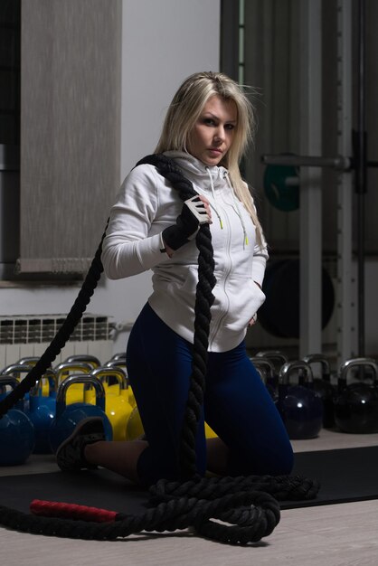 Attractive Woman Resting On Weights After Exercise In Fitness Center With Rope