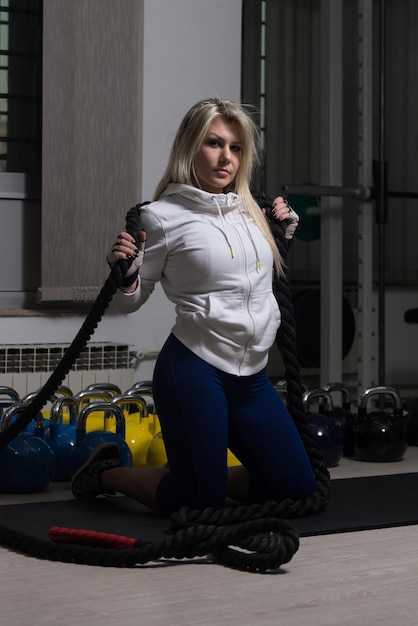 Attractive Woman Resting On Weights After Exercise In Fitness Center With Rope