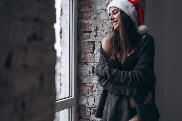 Donna attraente in un cappello di babbo natale e un maglione