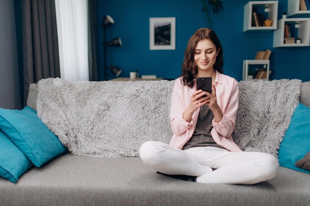 Foto attraente donna seduta sul divano e utilizza lo smartphone