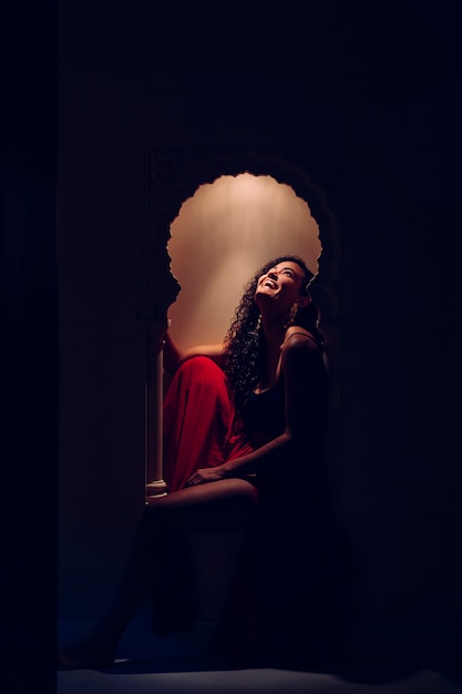 Attractive woman sitting on a decorated moroccan window at a hotel resort