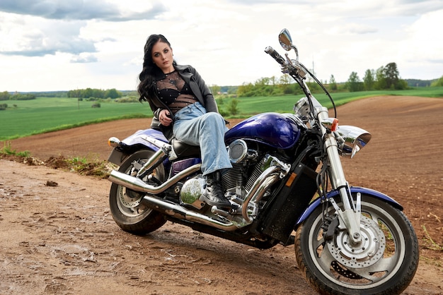 매력적인 여자는 필드에 일몰 오토바이에 앉아.