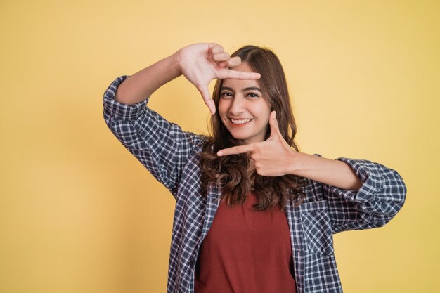 Attractive woman smiling with gesture making frame for her head with both fingers with copyspace