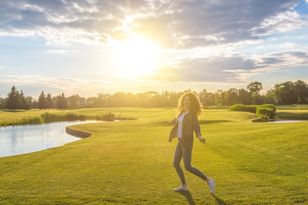 The attractive woman spinning on the grass on the sunshine background