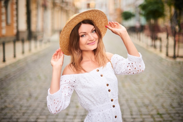 Attractive woman in straw hat and white sundress enjoying vacation