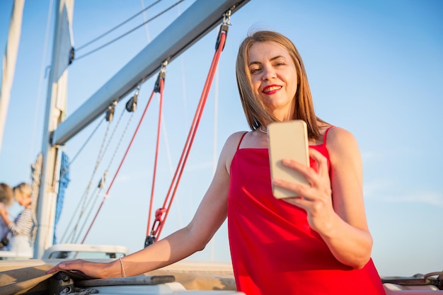 Attractive woman taking selfie photo on smartphone while standing on the river marina