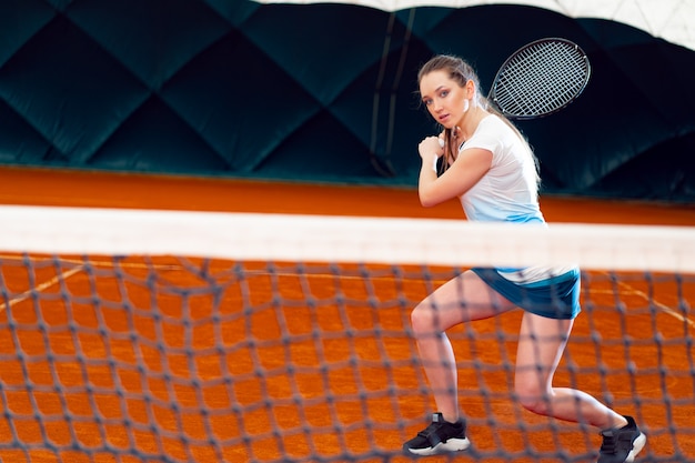 Привлекательная женщина-теннисистка ждет обслуживания на крытом корте