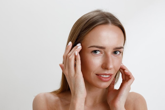 Attractive woman touching her perfect face over white studio background Healthcare routine concept