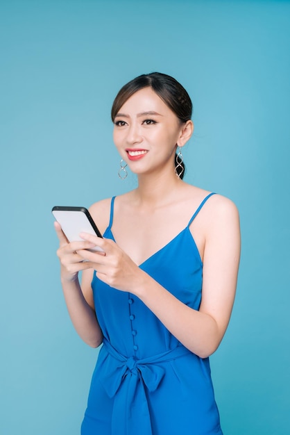 Attractive woman using text messaging feature on her portable device in studio