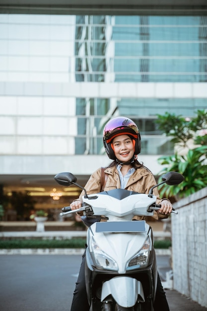 Attractive woman wearing helmet while riding motorcycle against building background