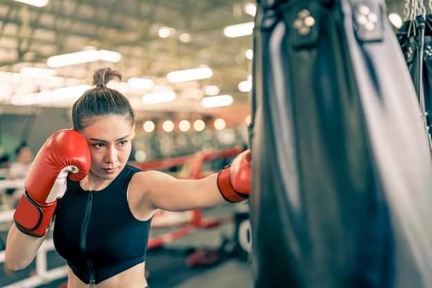 フィットネスジムで運動する準備ができているボクシンググローブを持つ魅力的な女性