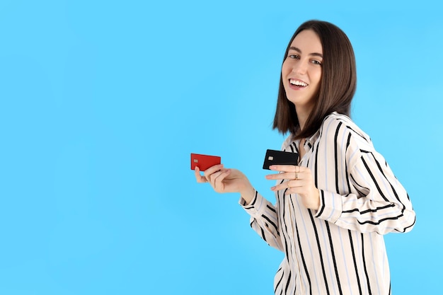 Attractive woman with cards on blue background