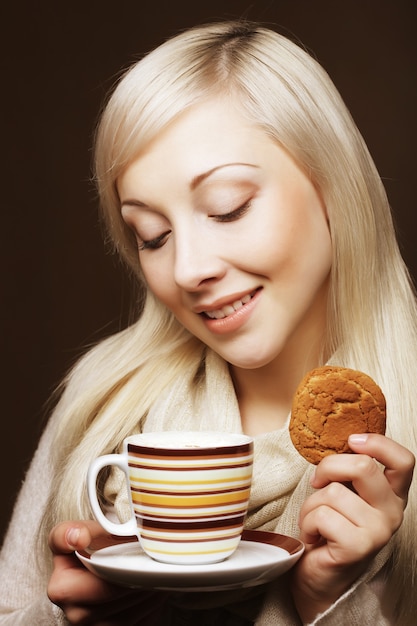コーヒーとクッキーを持つ魅力的な女性