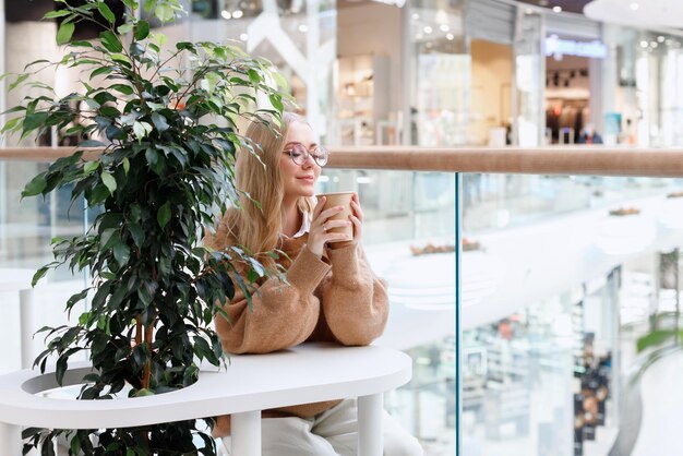 Attractive woman with a craft cup of coffee in the shopping center