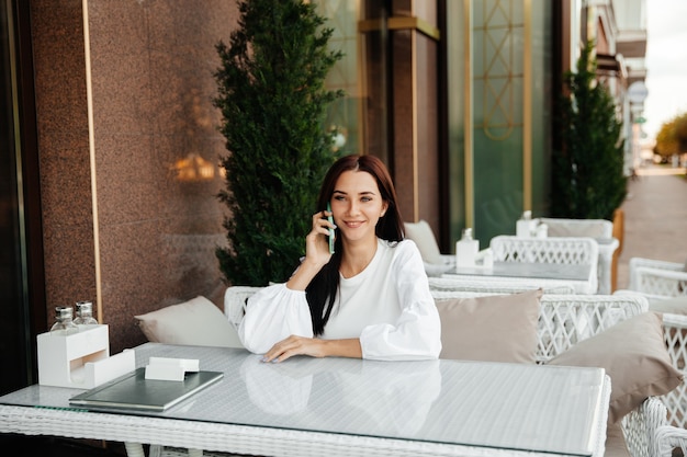 Attractive woman with a cute smile talking on a cell phone while relaxing in a cafe.