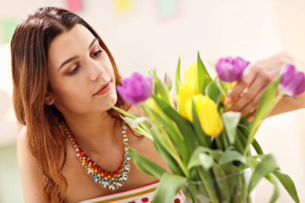 家に花を持つ魅力的な女性