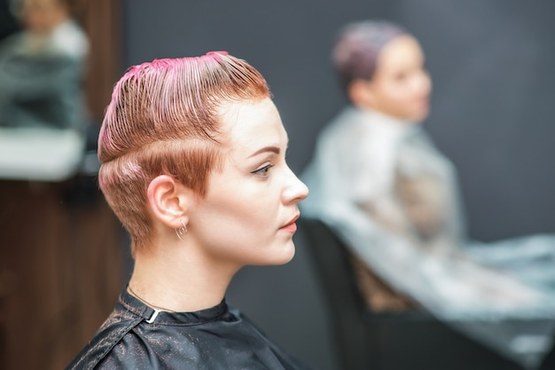 Attractive woman with glamour wet short pink hair at beauty salon.
