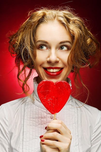 Foto donna attraente con caramello cuore su sfondo rosso