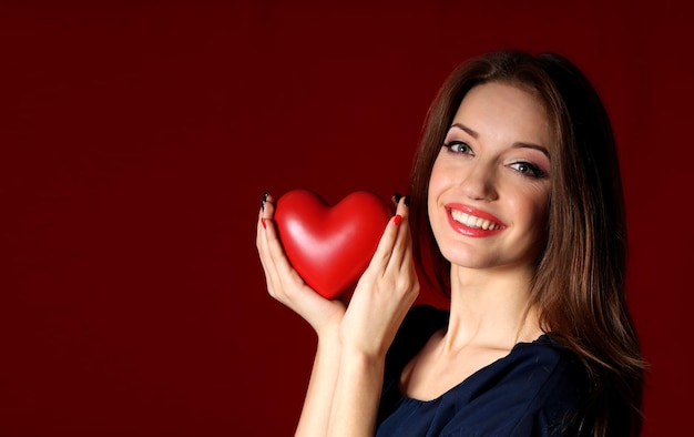 Attractive woman with heart, on red background