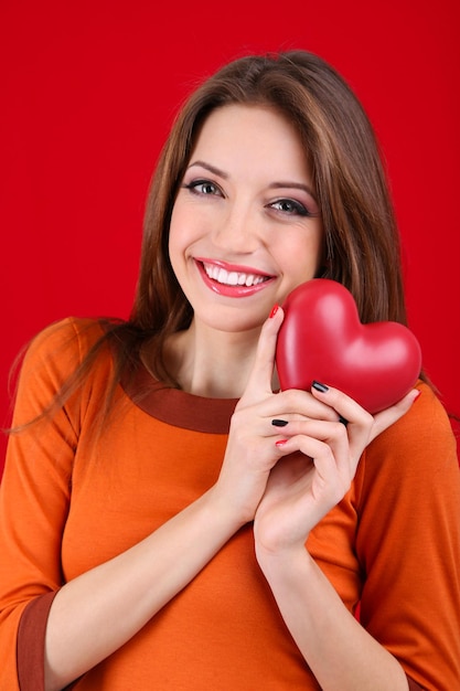 Attractive woman with heart, on red background