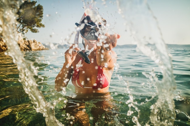 An attractive woman with her scuba mask and snorkel having fun in the sea water and enjoy on the beach vacation.