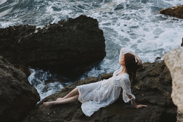 Attractive woman with long hair in a white dress lying on a stone in a white dress unaltered High quality photo