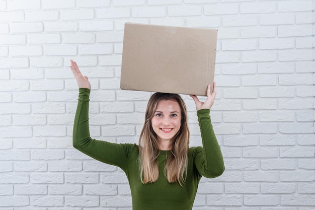 Attractive woman with parcel box on her head Delivering a parcel
