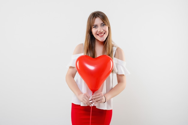 Attractive woman with red heart shaped balloon isolated