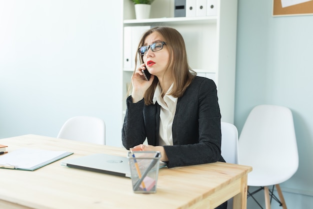 Attractive woman with red lips in office talking on phone